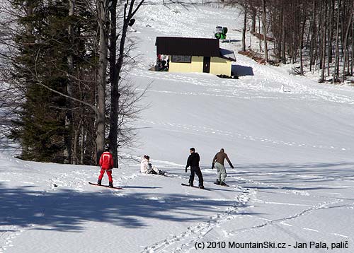 Tři maníci a jedna slečna pojížděli v dolní části u dvojsedačky na snowboardech